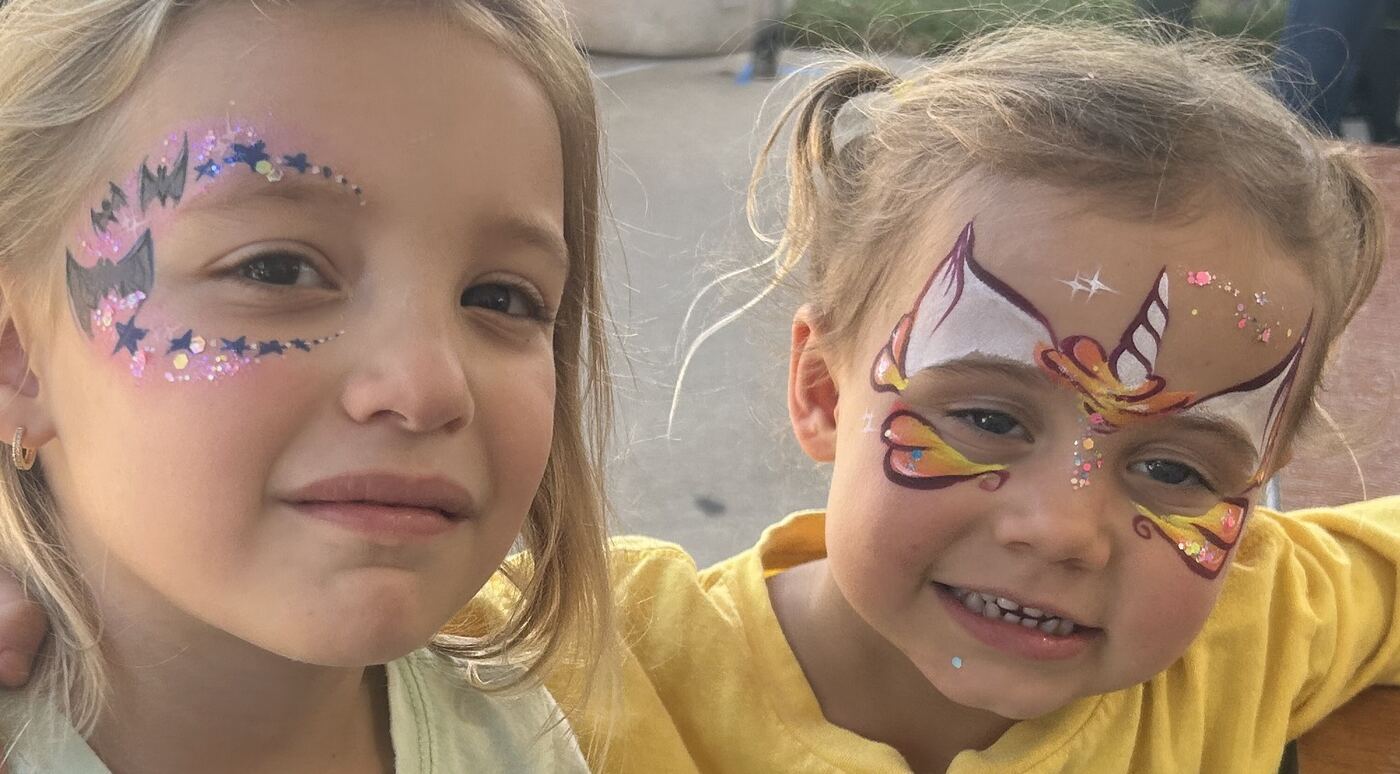Two smiling children with colorful face painting designs