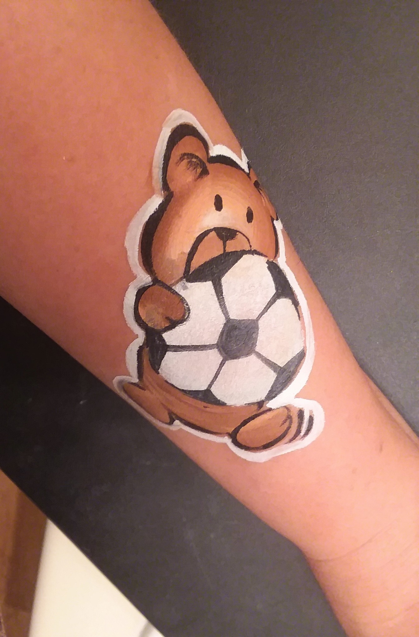 Bear holding a soccer ball painted on an arm